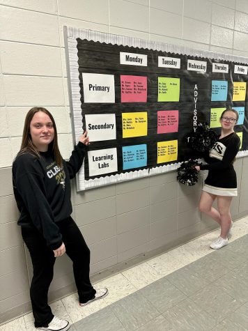 Sophomores Maddie Graves and Olivia Ware highlight the hallway bulletin board that informs students of the daily schedule for WIN time.